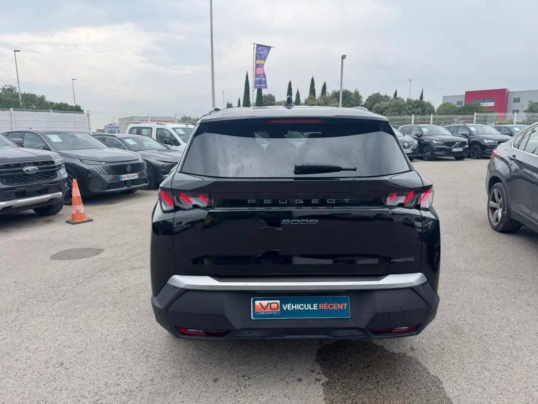 Vue arrière d’un Peugeot 5008 Hybrid noir 2025 avec feux arrière distinctifs en forme de griffes et plaque "Véhicule récent".