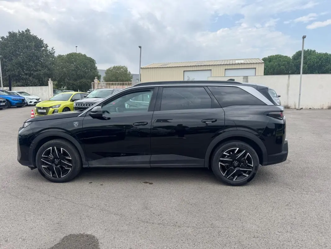 Peugeot 5008 Hybrid noir vue de profil côté gauche, avec jantes alliage noires et barres de toit visibles.