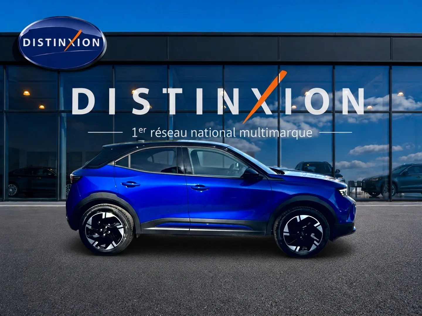 Opel Mokka Electric 156 GS bleu en profil droit devant une vitrine avec logo Distinxion.