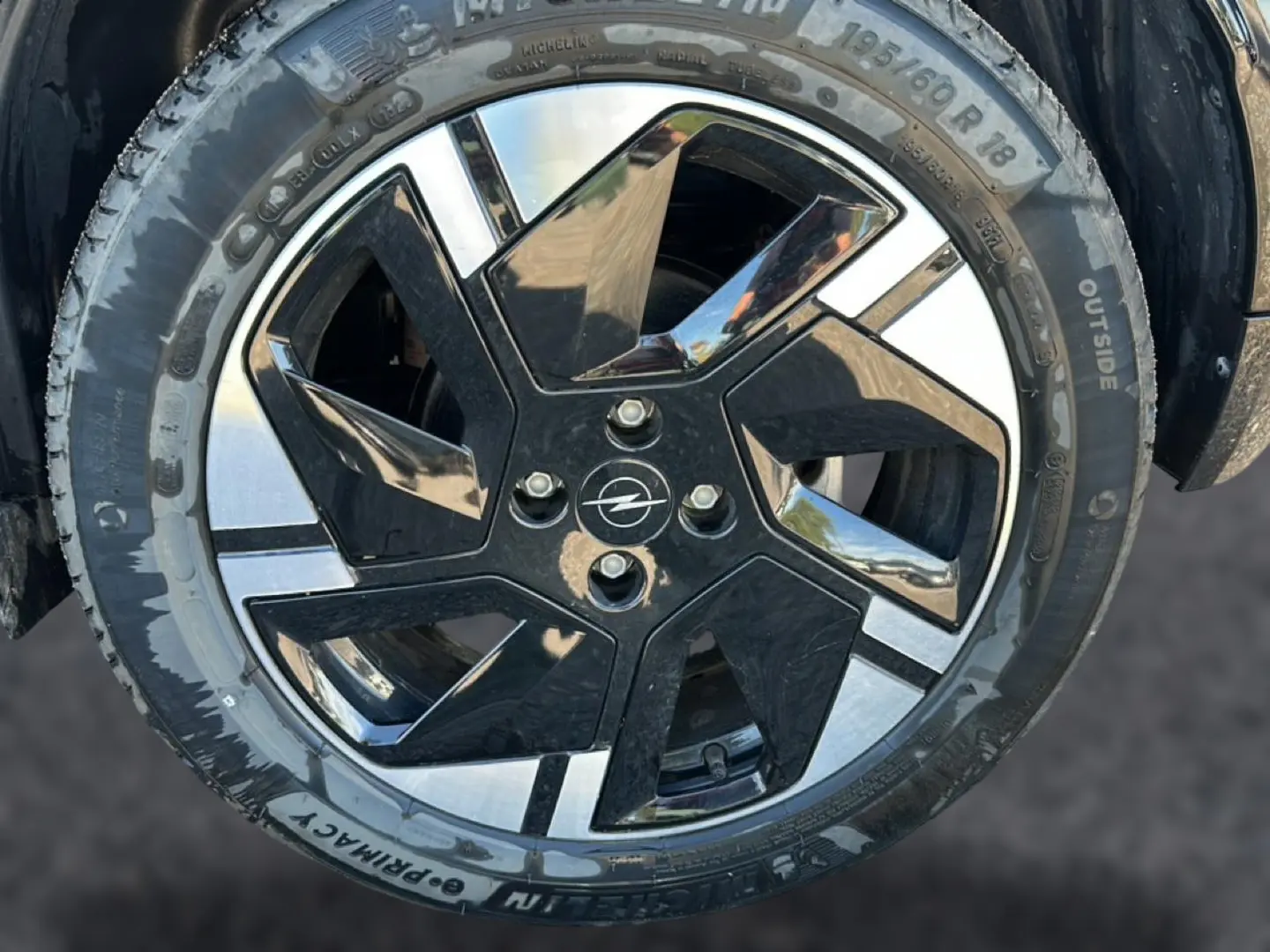 Gros plan sur la jante alu noire et argentée d’un Opel Mokka Electric 156 gs bleu, avec logo Opel au centre.