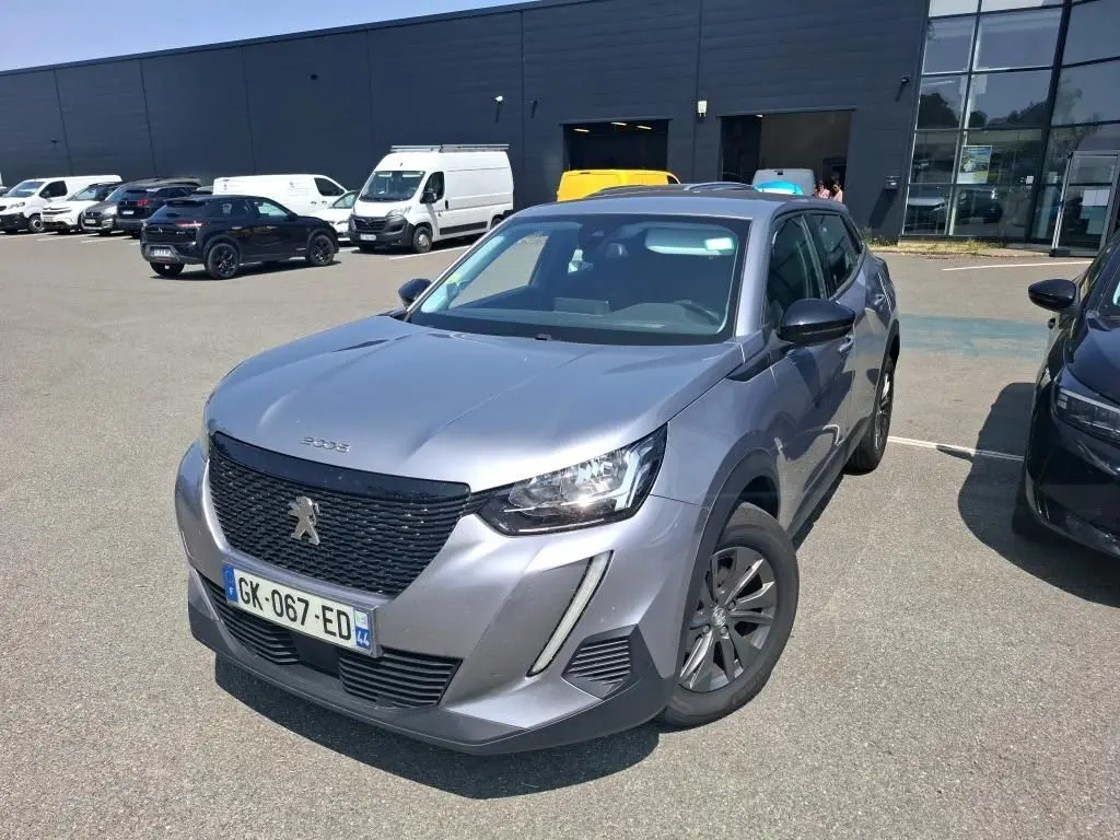 Peugeot 2008 gris Artense vue 3/4 avant droit, avec calandre noire et jantes foncées sur parking extérieur.
