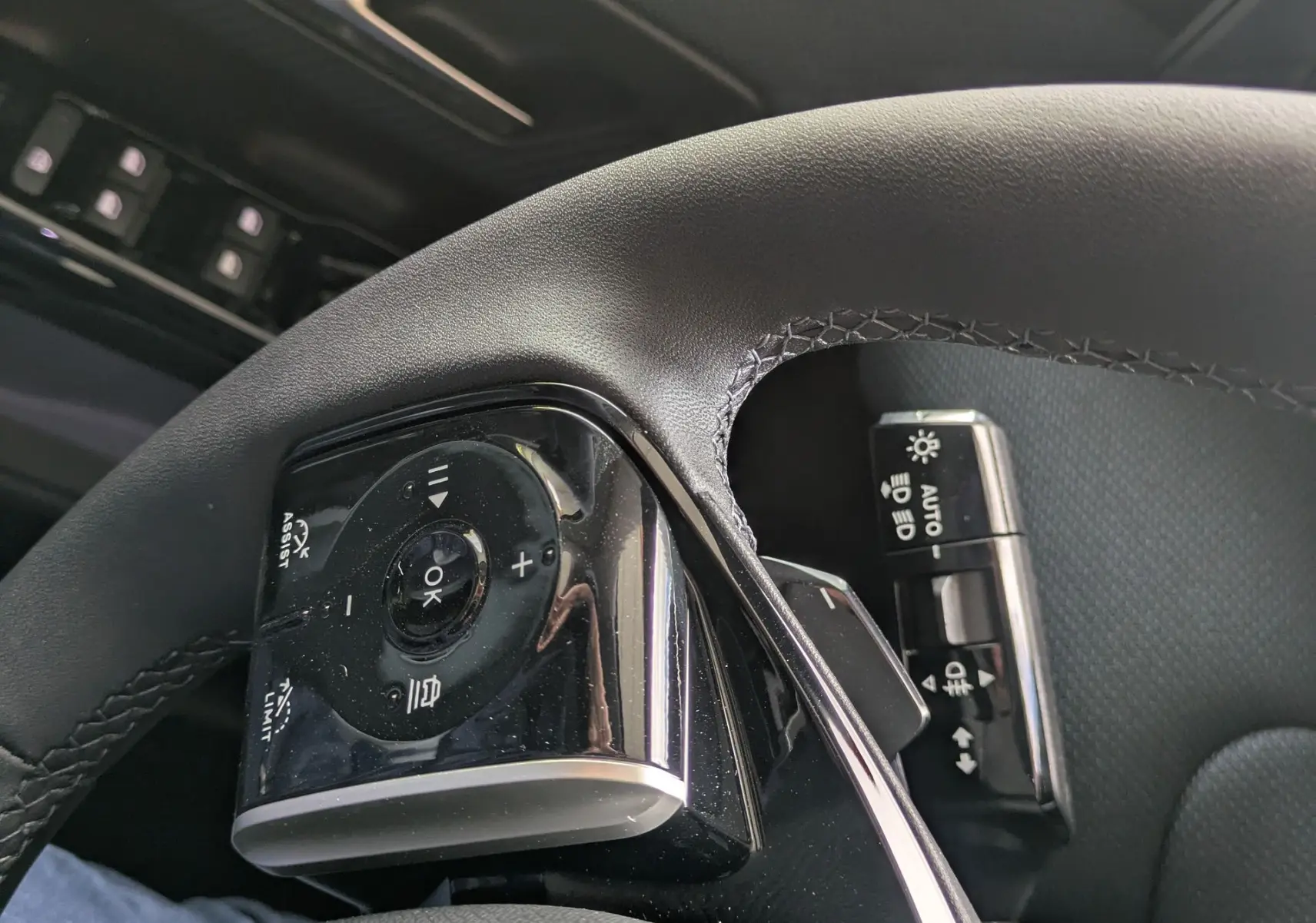 Gros plan sur les commandes au volant côté gauche du Citroën C5 Aircross hybride 2026, intérieur noir.