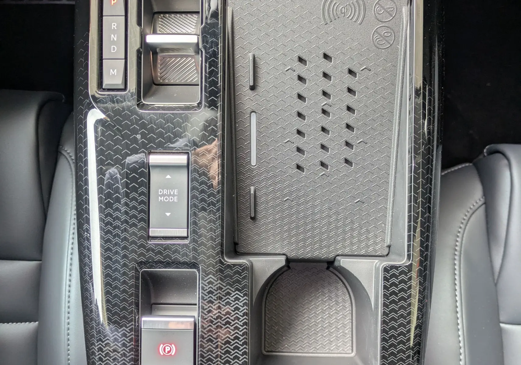 Vue plongeante sur la console centrale noire brillante du Citroën C5 Aircross hybride 2026 avec commandes de boîte auto et zone de recharge sans fil.