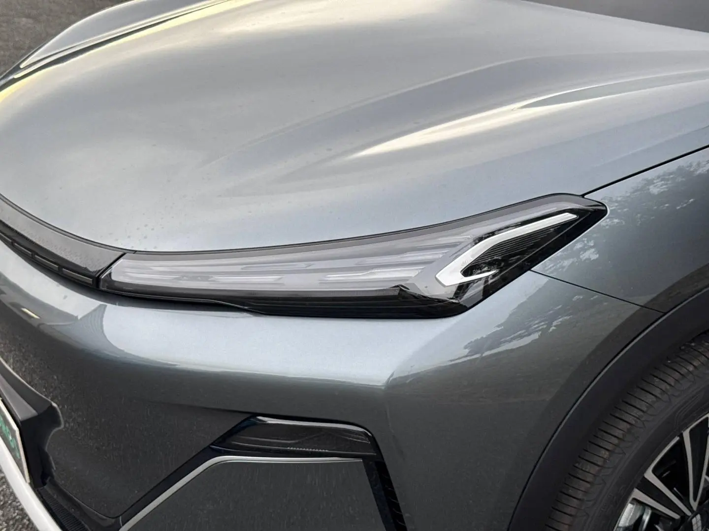 Gros plan sur l'avant droit du Geely STARRAY 1.5 EM-i 262ch Max+ en Volcanic Grey Metallic, mettant en valeur le phare LED.