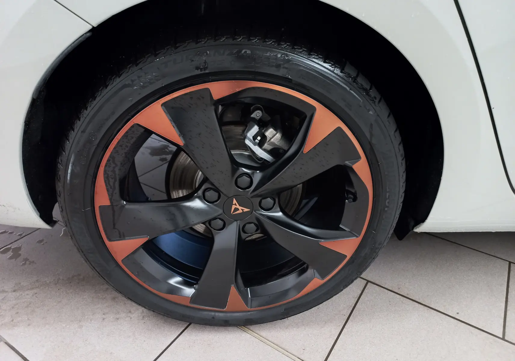 Gros plan sur la jante 18'' cuivrée et noire du CUPRA LEON ST 2025, avec partie de la carrosserie gris Taiga visible.