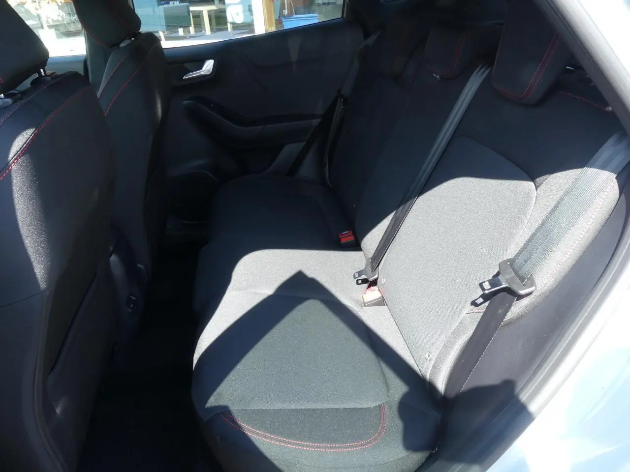 Vue intérieure côté droit des sièges arrière en tissu noir avec surpiqûres rouges du Ford Puma 2025 gris métallisé.