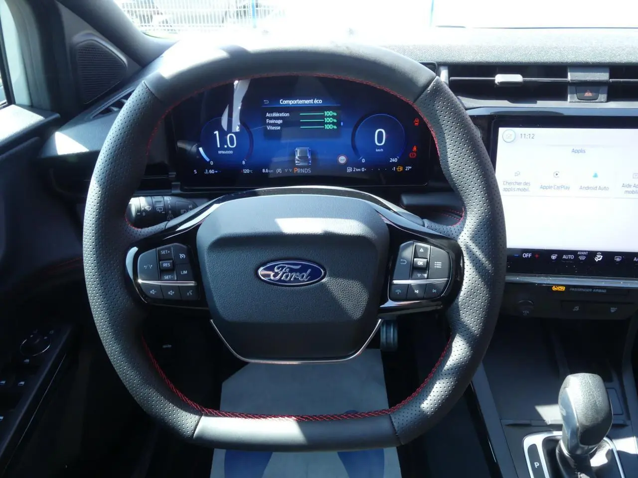 Vue rapprochée du volant perforé avec surpiqûres rouges et tableau de bord numérique du Ford Puma 2025 ST-Line.