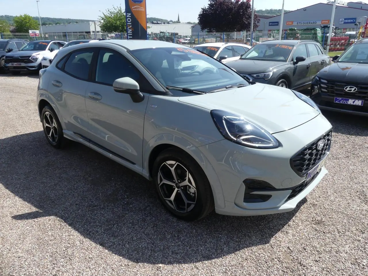 Ford Puma 2025 gris métallisé en 3/4 avant droit, avec jantes alliage et calandre noire sportive ST-Line.
