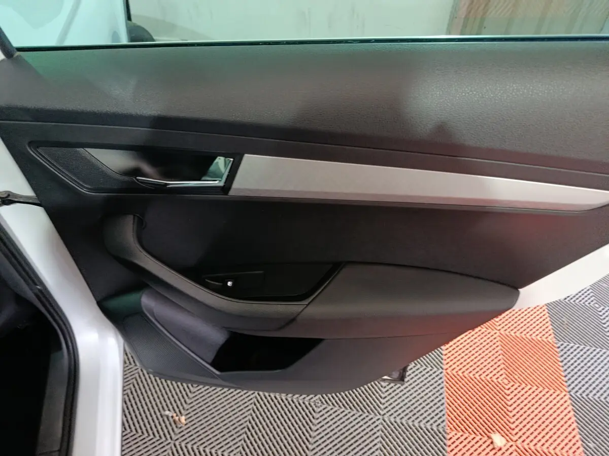 Vue intérieure côté gauche de la porte avant d'une Skoda Karoq 2024, avec garniture noire et insert argenté.