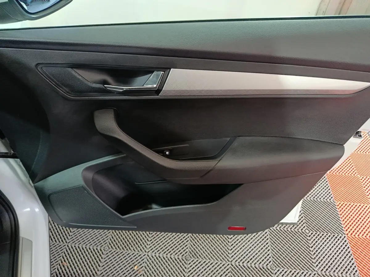 Vue intérieure de la porte côté gauche noire avec poignée argentée et insert décoratif gris du Skoda Karoq 2024.
