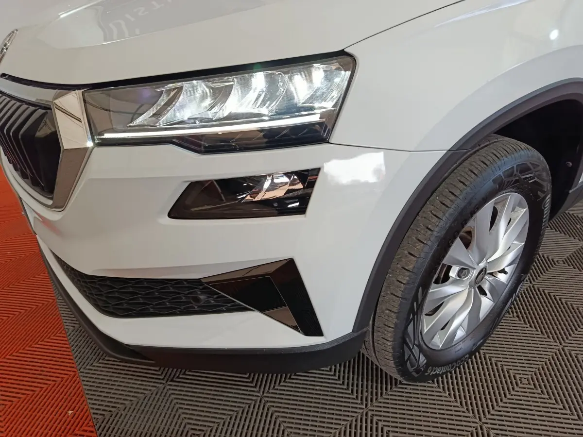 Gros plan sur l'avant droit blanc du Skoda Karoq 2024, mettant en valeur le phare LED et la roue alliage.