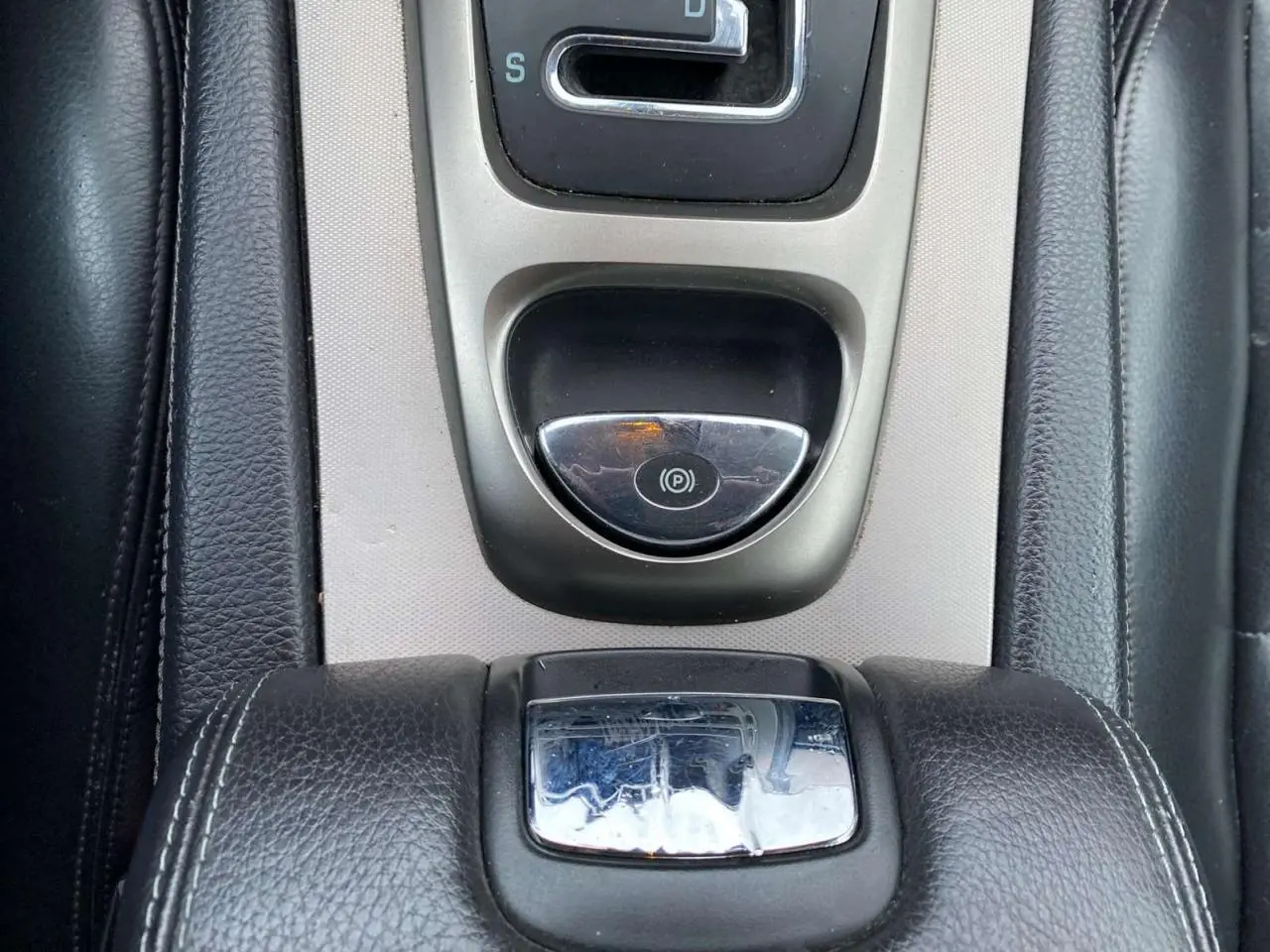 Vue rapprochée de la console centrale en cuir noir et aluminium du Jaguar XK Coupé gris clair 2009 avec frein à main électrique.