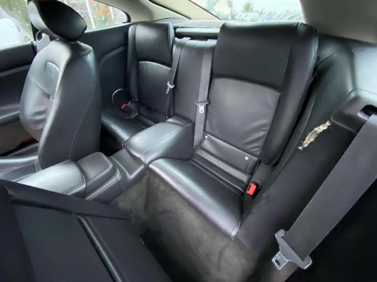 Intérieur arrière du coupé Jaguar XK 4.2i V8 2009, sièges cuir noir vus en plongée côté droit.