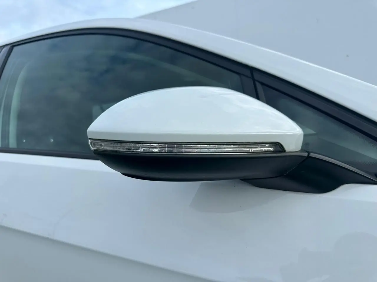 Rétroviseur latéral gauche blanc de Volkswagen Golf VII 2018, avec clignotant intégré visible sur fond de portière.