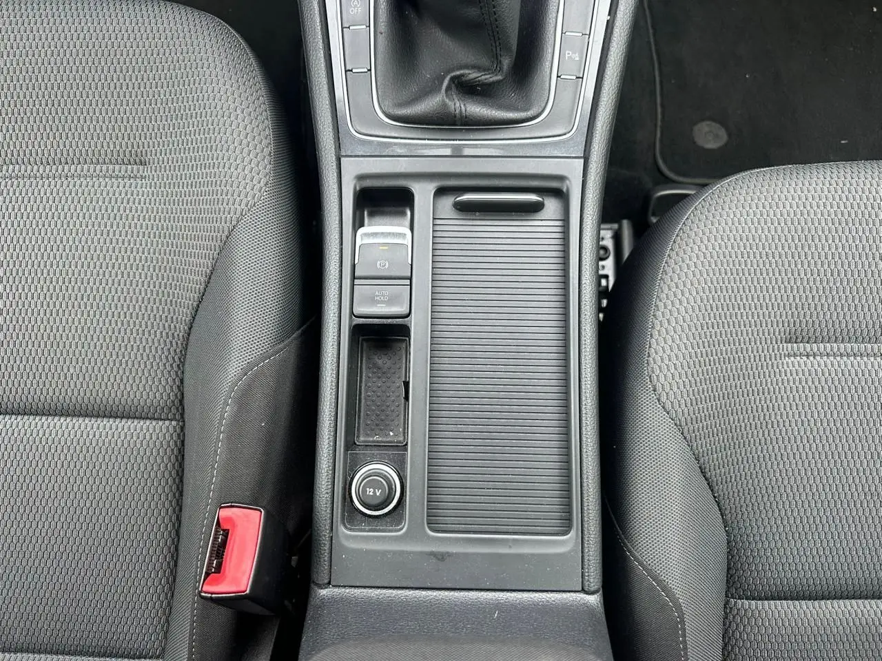 Vue plongeante sur la console centrale noire et les sièges tissu gris de la Volkswagen Golf VII 2.0 TDI.