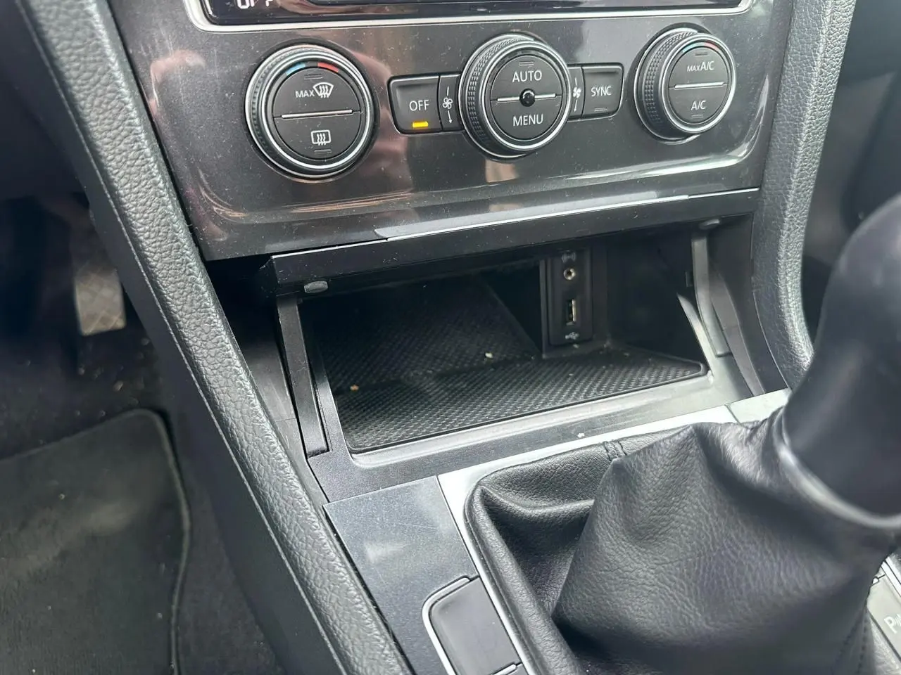 Gros plan sur la console centrale intérieure noire de la Volkswagen Golf VII avec boîte manuelle et commandes climatisation.