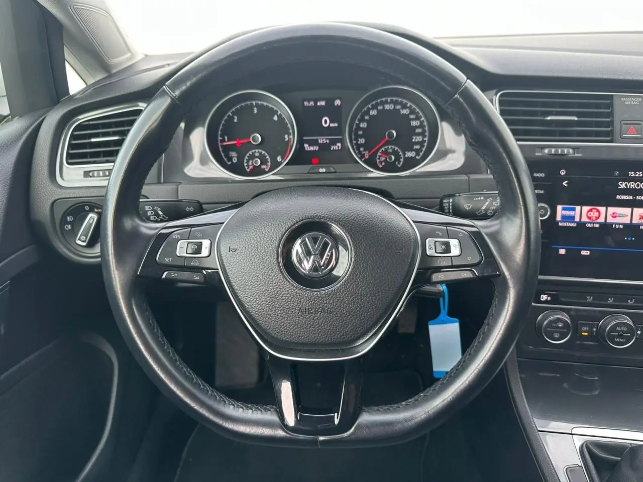 Vue intérieure centrée sur le volant en cuir noir d'une Volkswagen Golf VII avec tableau de bord et écran tactile.