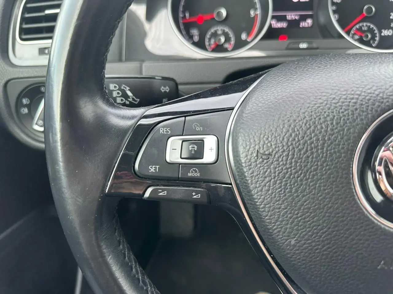Gros plan sur le volant multifonction en cuir noir d'une Volkswagen Golf VII 2018, avec commandes de régulateur de vitesse.