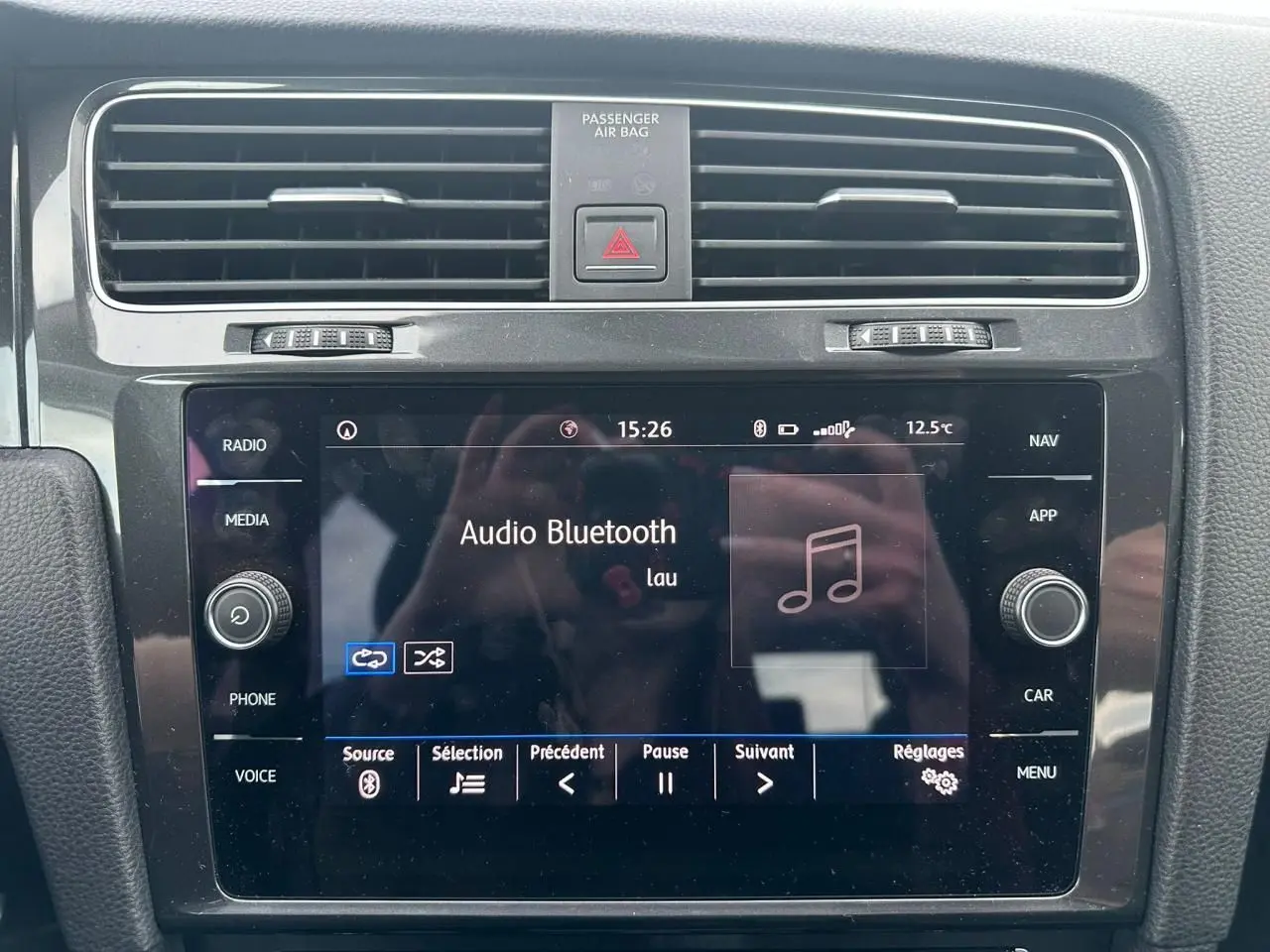 Vue rapprochée de la console centrale noire de la Volkswagen Golf VII avec écran tactile affichant l'audio Bluetooth.