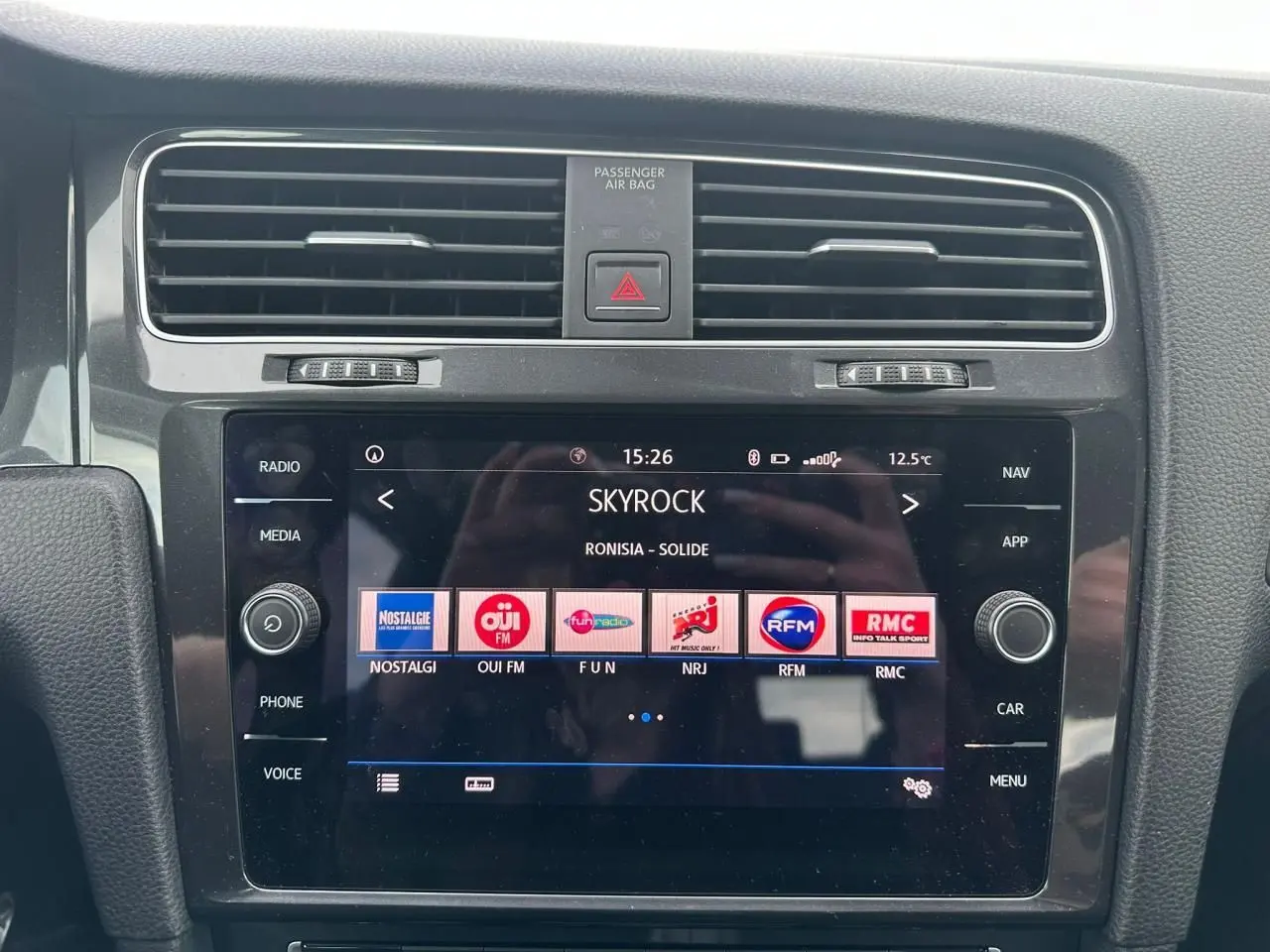 Vue rapprochée de la console centrale de la Volkswagen Golf VII blanche, affichant l'écran tactile multimédia.