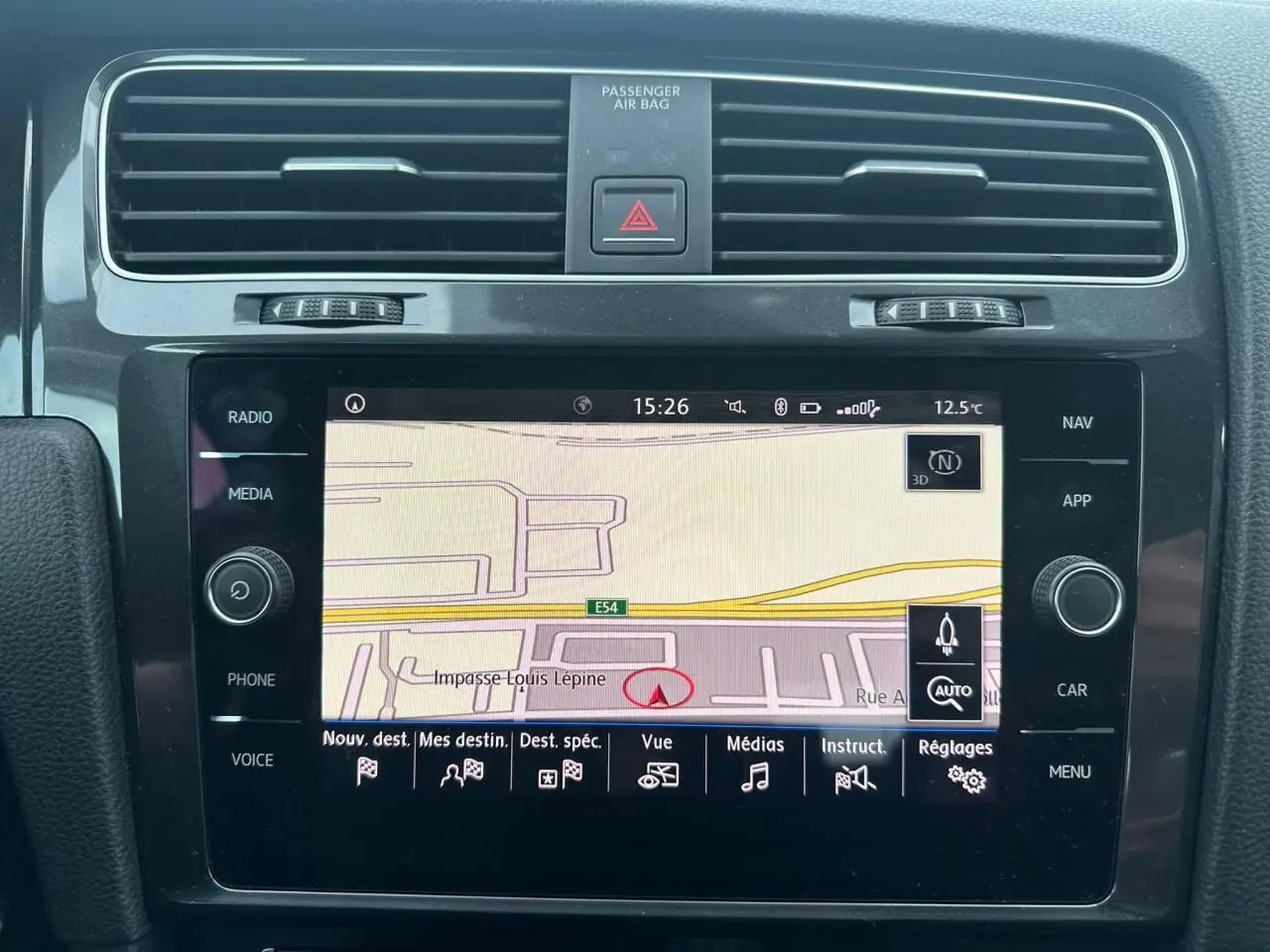 Vue rapprochée de l’écran tactile central noir affichant la navigation GPS dans une Volkswagen Golf blanche de 2018.