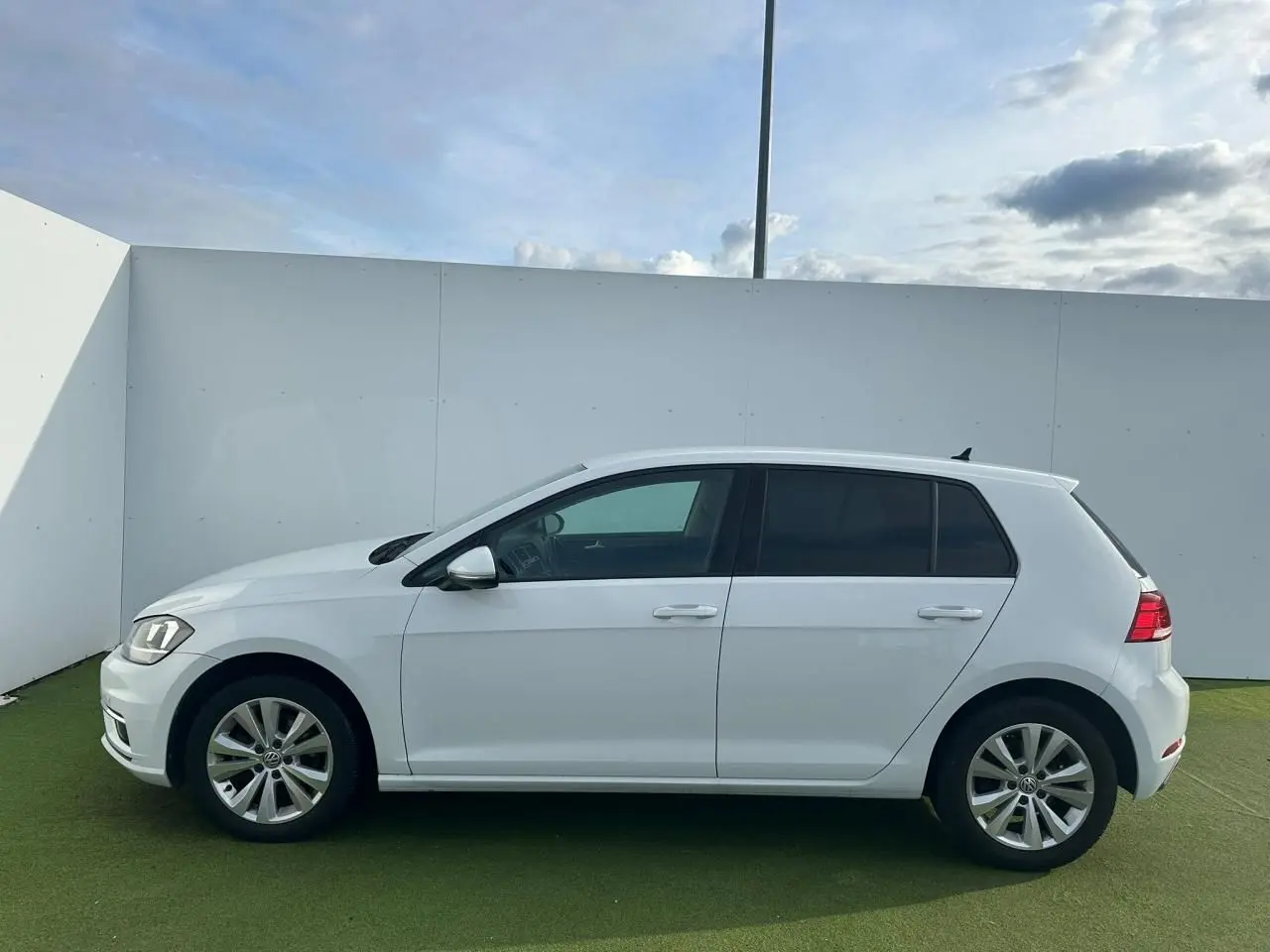 Profil droit d'une Volkswagen Golf VII blanche de 2018, avec jantes alliage 16 pouces et vitres teintées.