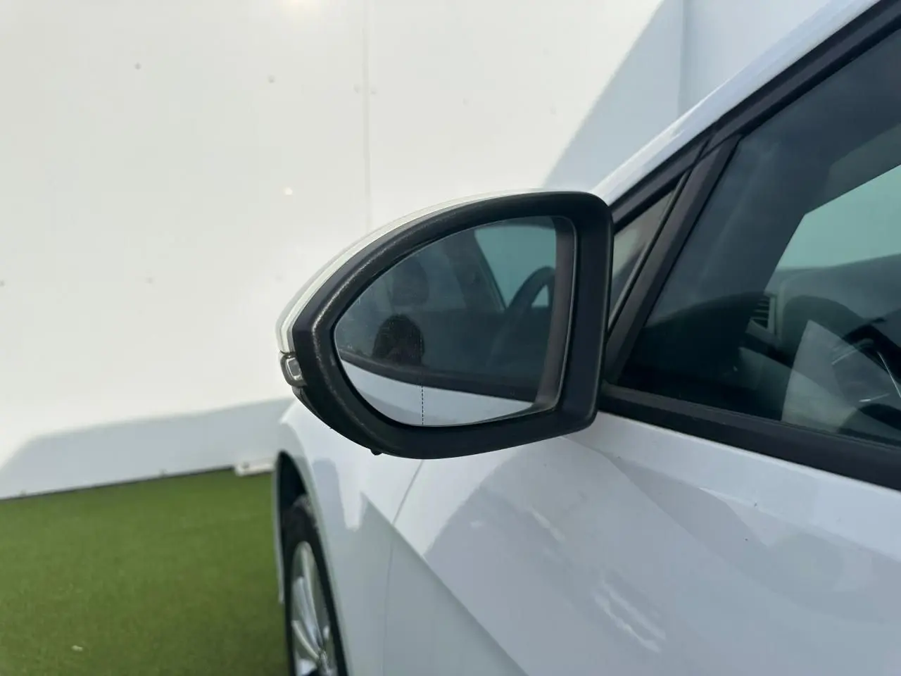 Vue rapprochée du rétroviseur extérieur droit d'une Volkswagen Golf VII blanche, avec partie avant et vitre latérale visibles.