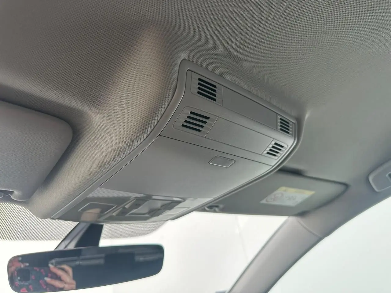 Vue intérieure du plafond avant gris clair de la Volkswagen Golf VII avec plafonnier et bouches d'aération intégrées.