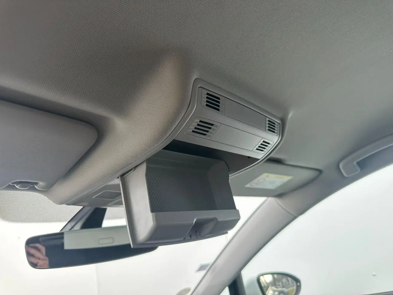 Détail du rangement plafond ouvert au-dessus du rétroviseur intérieur dans une Volkswagen Golf VII blanche de 2018.