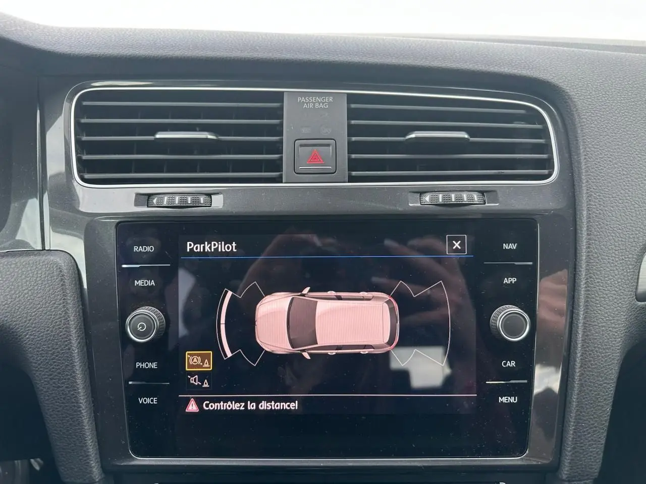 Écran tactile central de la Volkswagen Golf VII blanc montrant l'alerte ParkPilot pour aide au stationnement.