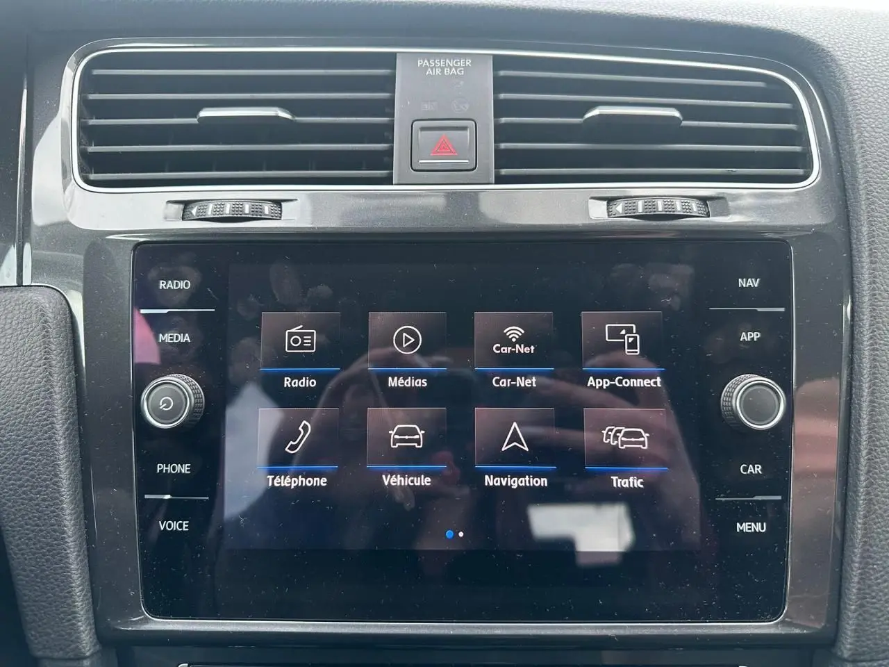 Écran tactile central de la Volkswagen Golf VII blanc, vue frontale du système multimédia avec commandes autour.