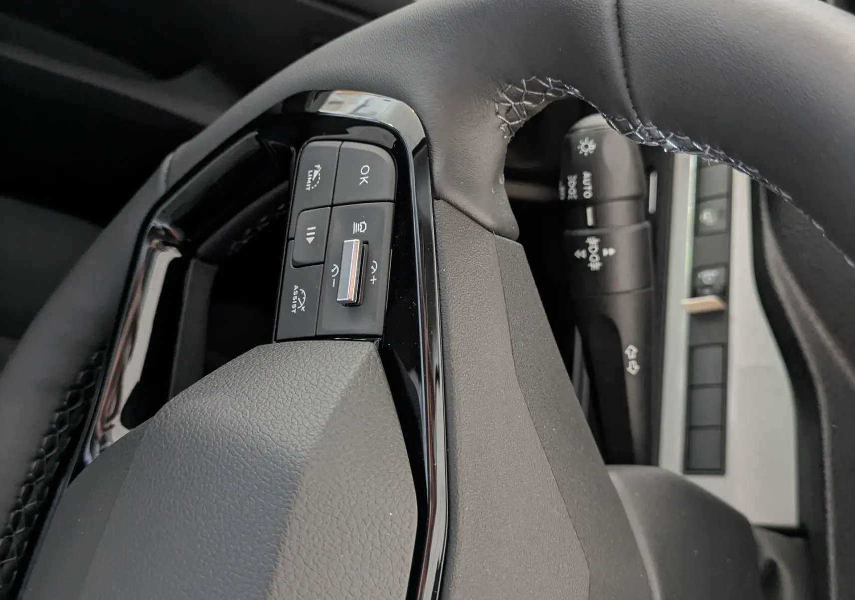 Gros plan sur le volant cuir noir du Peugeot Traveller 2026, avec commandes intégrées et logo Peugeot visible.
