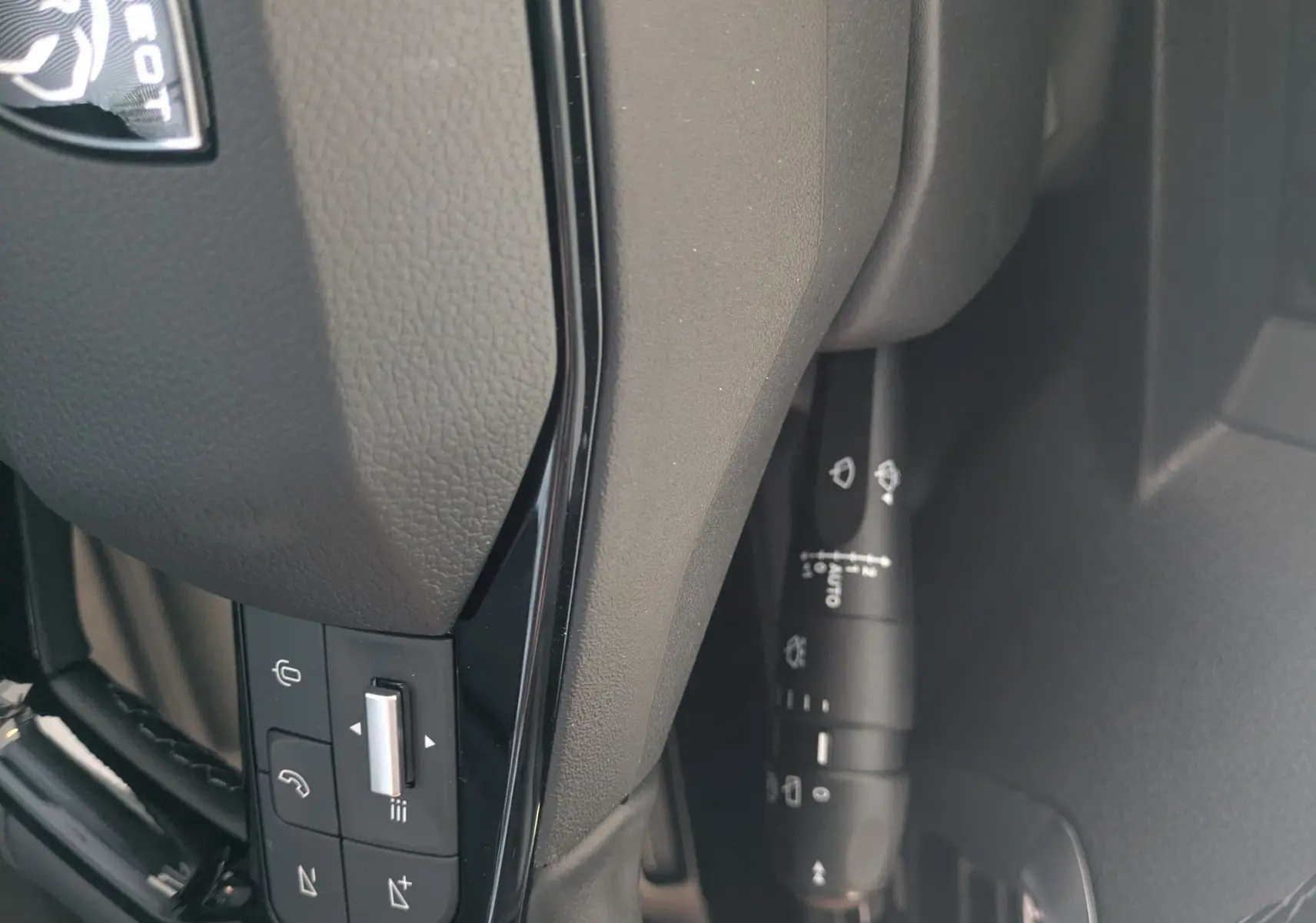Gros plan sur le volant cuir noir du Peugeot Traveller 2026 avec commandes intégrées et logo Peugeot visible.