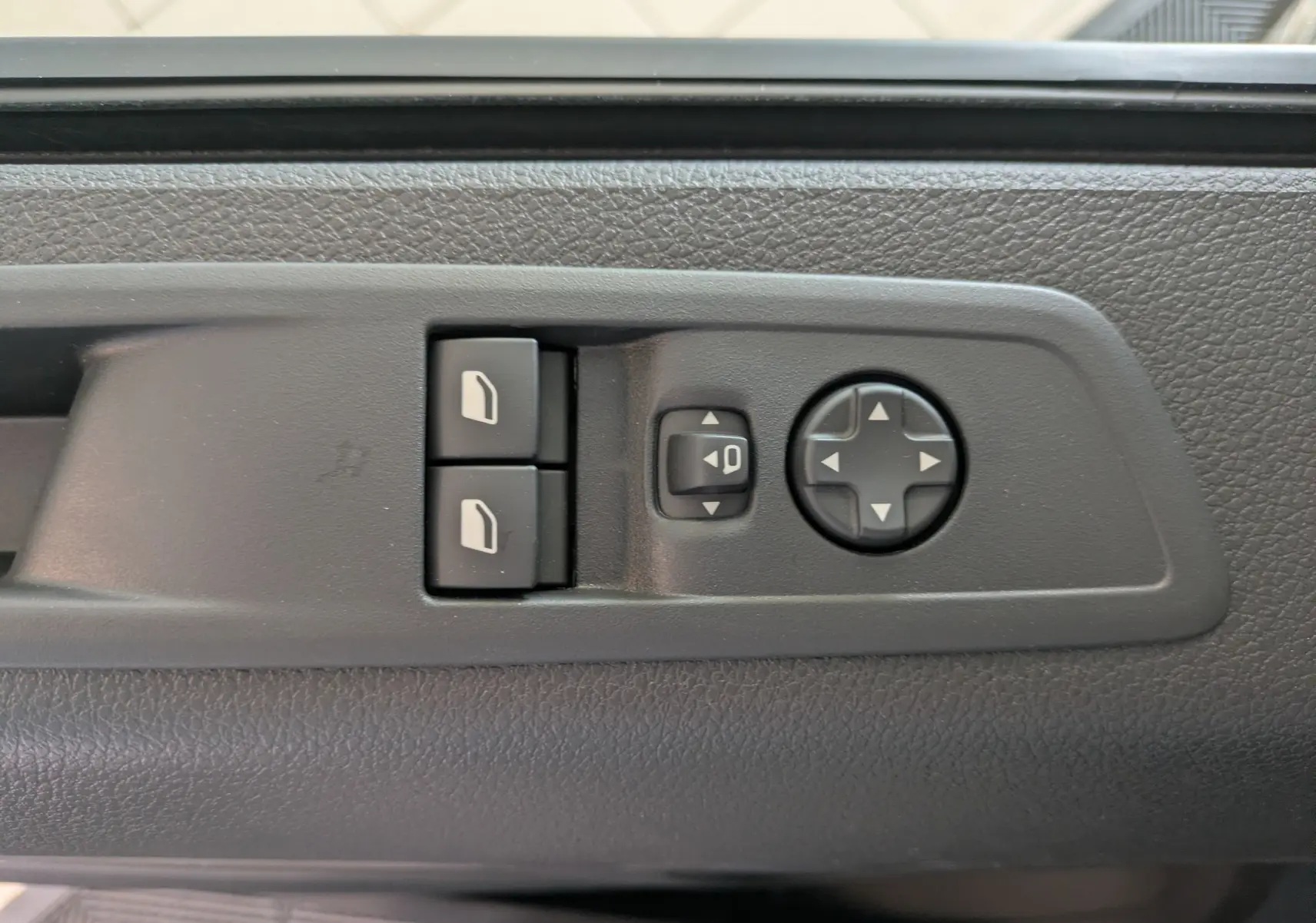 Gros plan sur les commandes de réglage des rétroviseurs électriques côté conducteur du Peugeot Traveller noir 2026.
