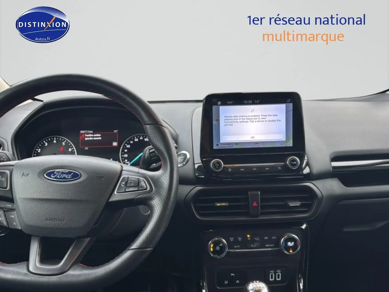 Vue intérieure du tableau de bord noir du Ford EcoSport 2019 avec volant cuir et écran tactile central allumé.