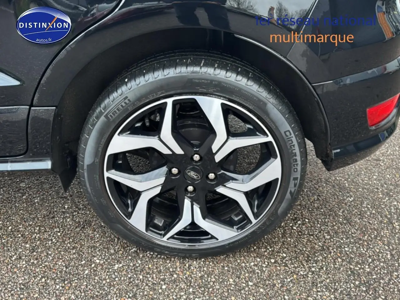 Gros plan sur la roue avant droite du Ford EcoSport noir avec jante alu bicolore et logo Ford visible.