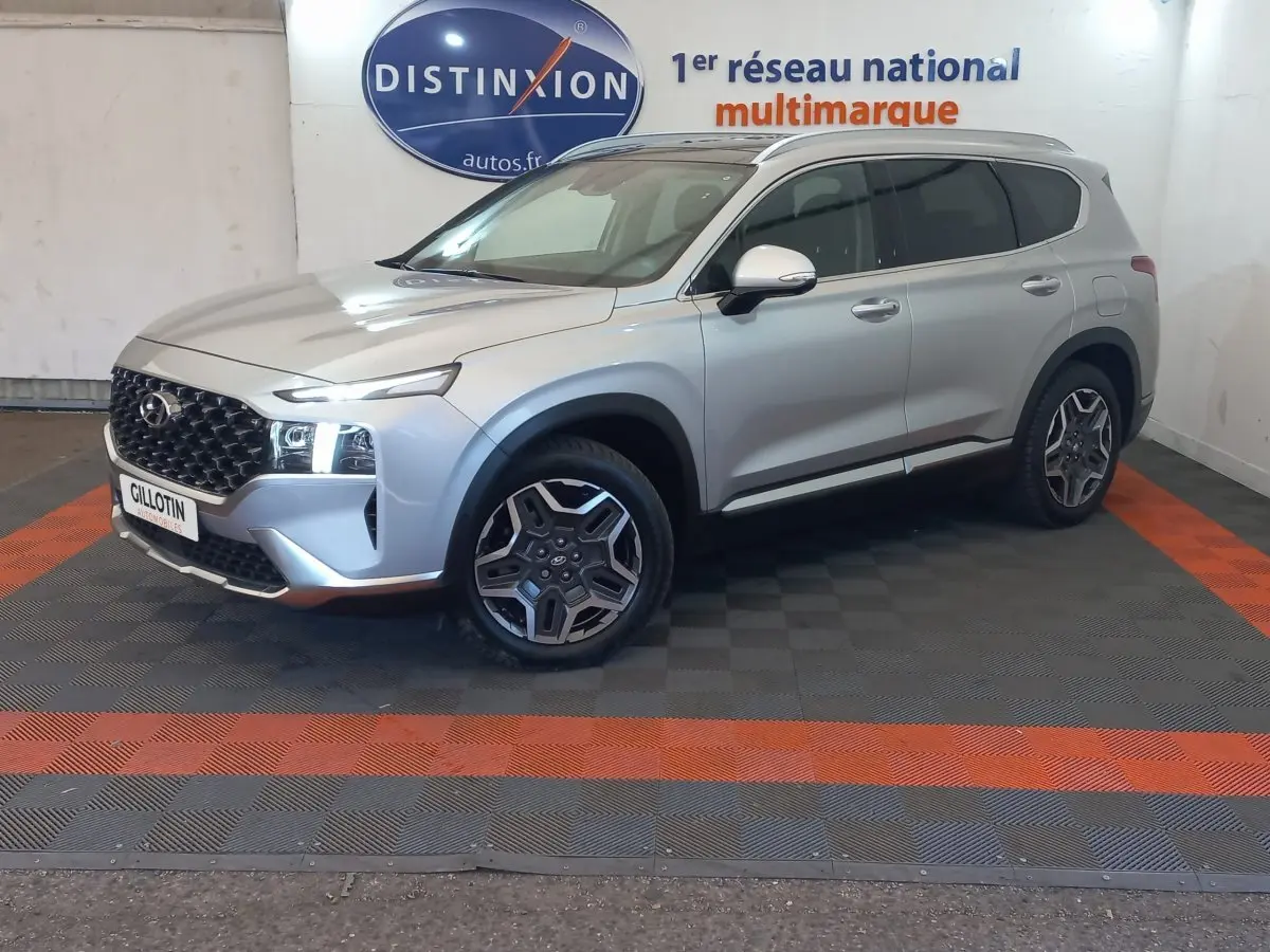 Hyundai Santa Fe gris clair en 3/4 avant droit, avec calandre noire et jantes alliage distinctives.