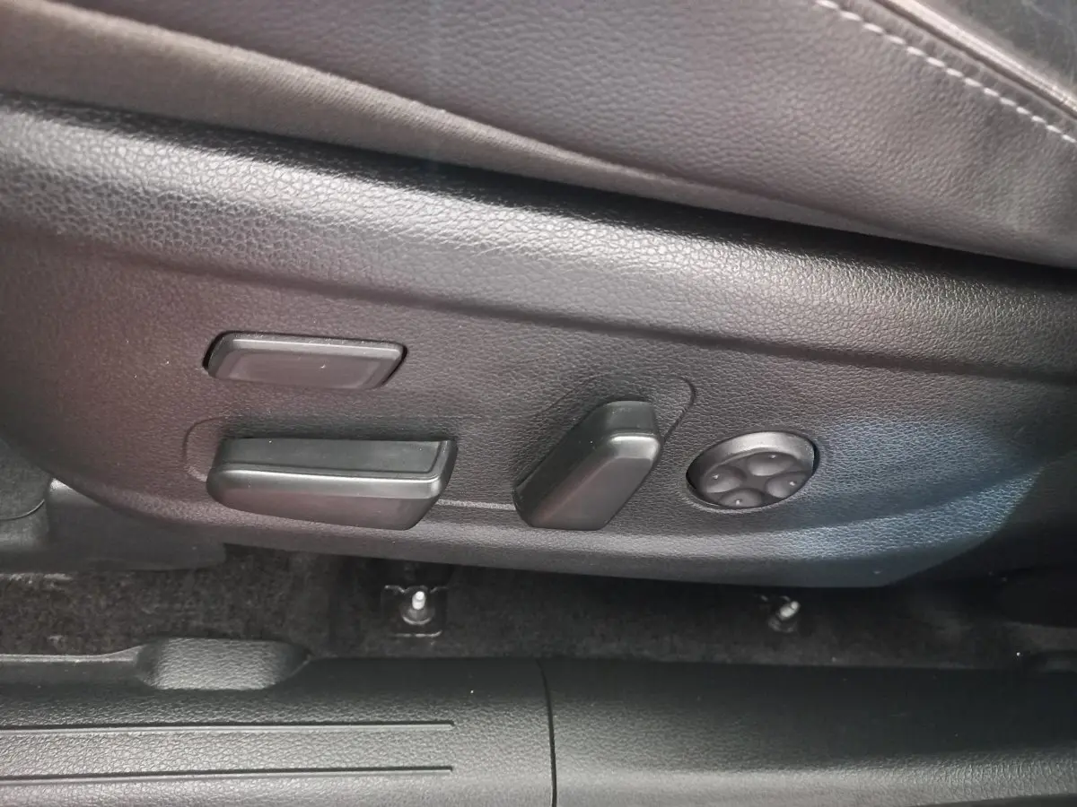 Gros plan sur les commandes de réglage électrique du siège conducteur noir dans un Hyundai Santa Fe gris clair 2021.