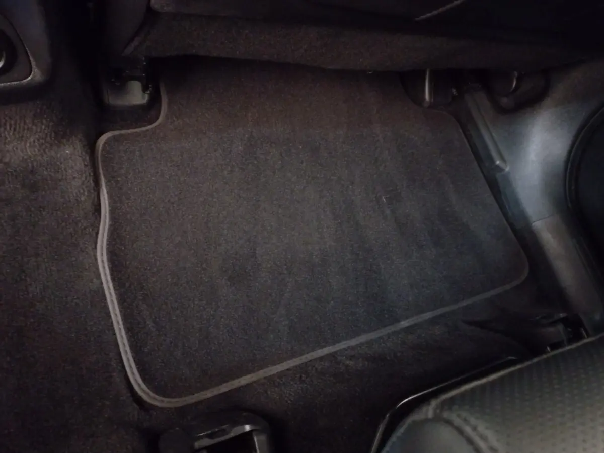 Tapis de sol noir côté passager avant du Hyundai Santa Fe hybride rechargeable gris clair, vue intérieure rapprochée.