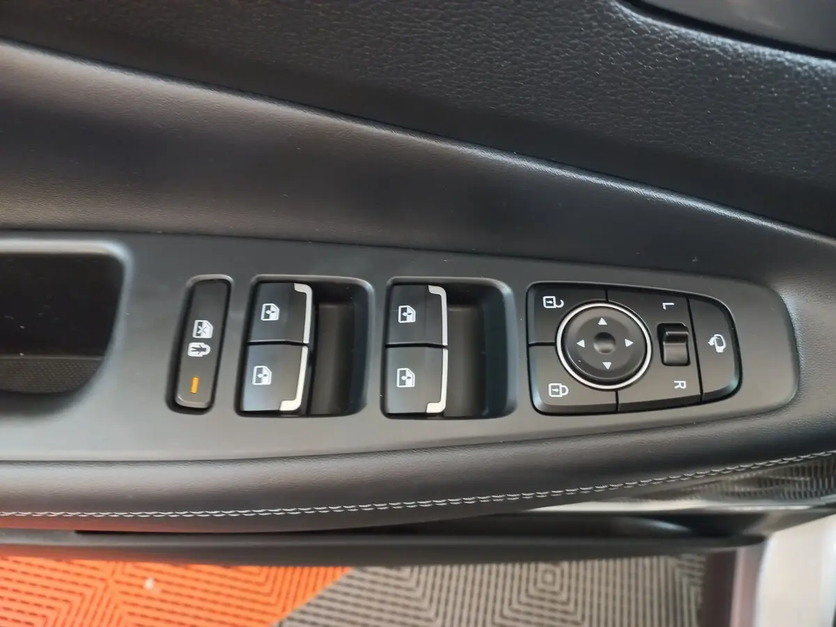 Gros plan sur les commandes de lève-vitres et réglages des rétroviseurs côté conducteur du Hyundai Santa Fe gris clair.