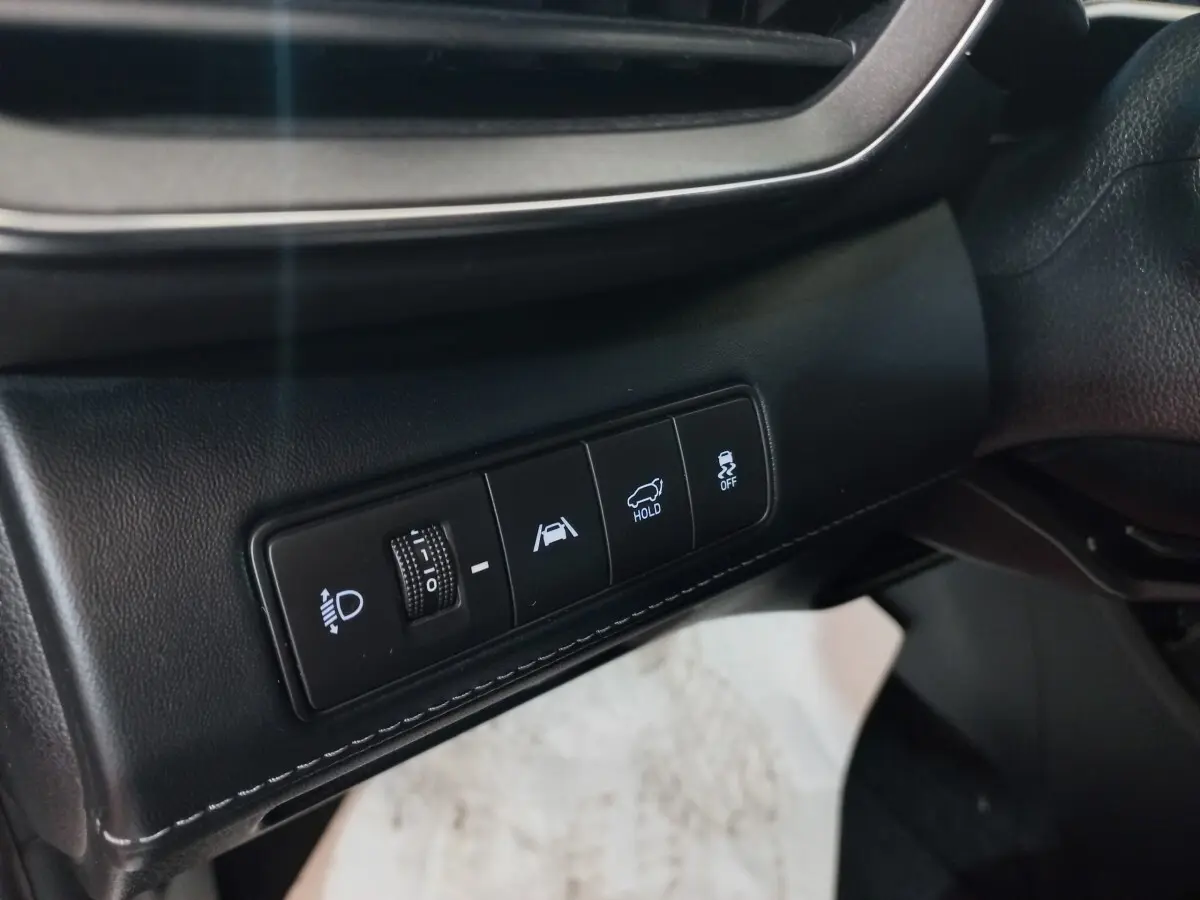 Gros plan sur les commandes noires du tableau de bord côté gauche du Hyundai Santa Fe gris clair hybride rechargeable.