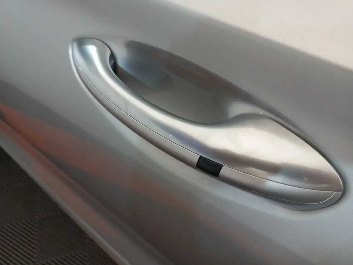 Poignée de porte côté droit gris clair du Hyundai Santa Fe hybride rechargeable 2021, finition lisse avec bouton noir intégré.