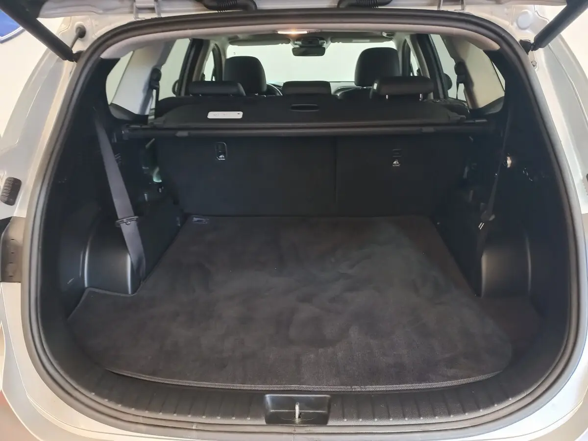 Coffre ouvert vu de l’arrière d’un Hyundai Santa Fe gris clair, montrant l’espace de chargement et la banquette arrière.