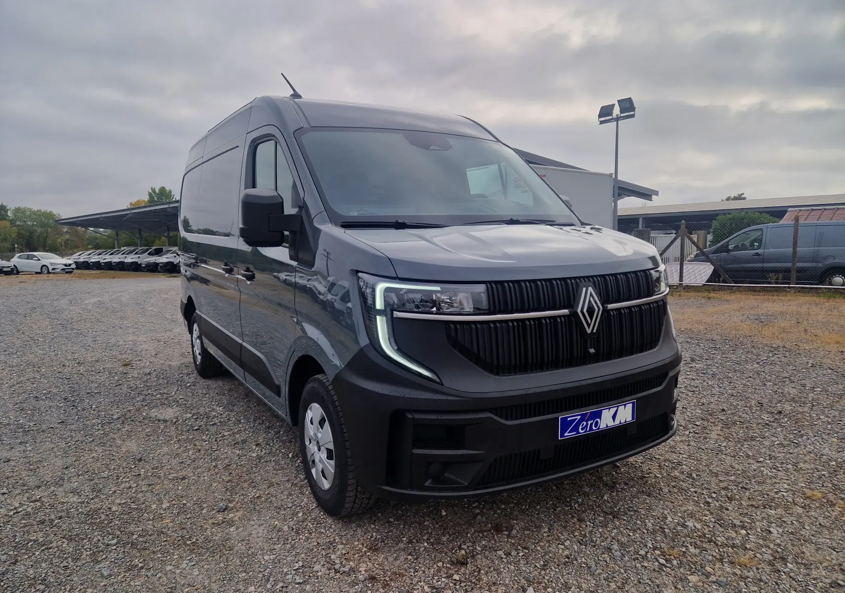 Renault Master gris urbain vu en 3/4 avant droit, avec calandre noire et feux LED en forme de C.