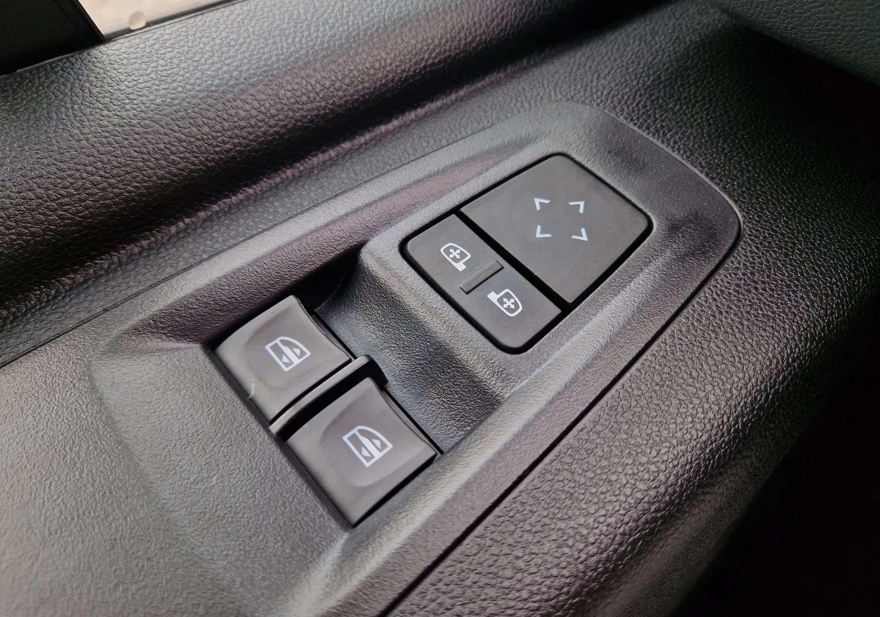 Gros plan sur les commandes de réglage des rétroviseurs et des vitres électriques côté conducteur du Renault Master gris urbain 2026.
