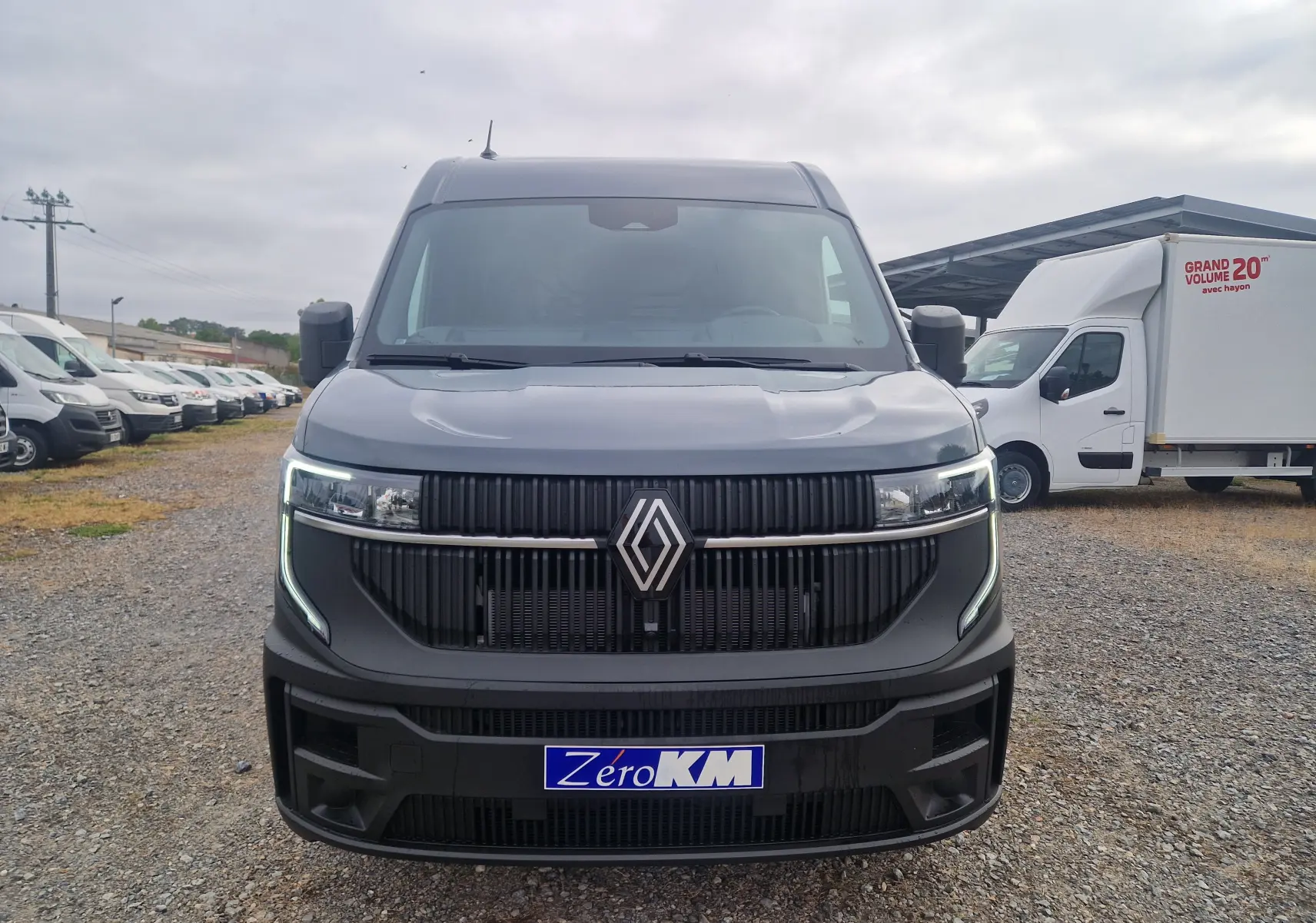 Vue frontale d’un Renault Master L2H2 gris urbain 2026 avec calandre noire et phares LED allumés sur un parking.