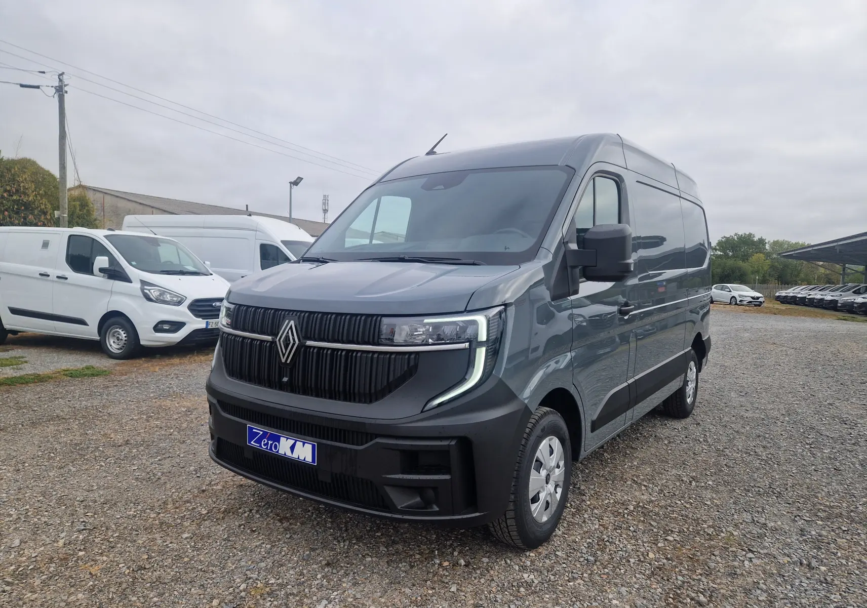 Renault Master gris urbain en vue 3/4 avant droit, avec calandre noire et feux LED en forme de C.