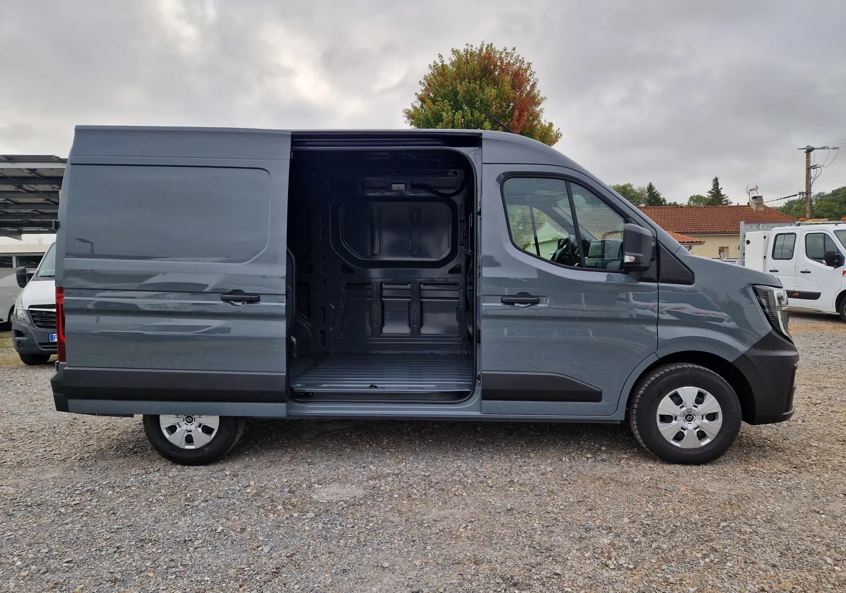 Renault Master L2H2 gris urbain vu de profil droit, porte latérale coulissante ouverte montrant l’espace de chargement vide.