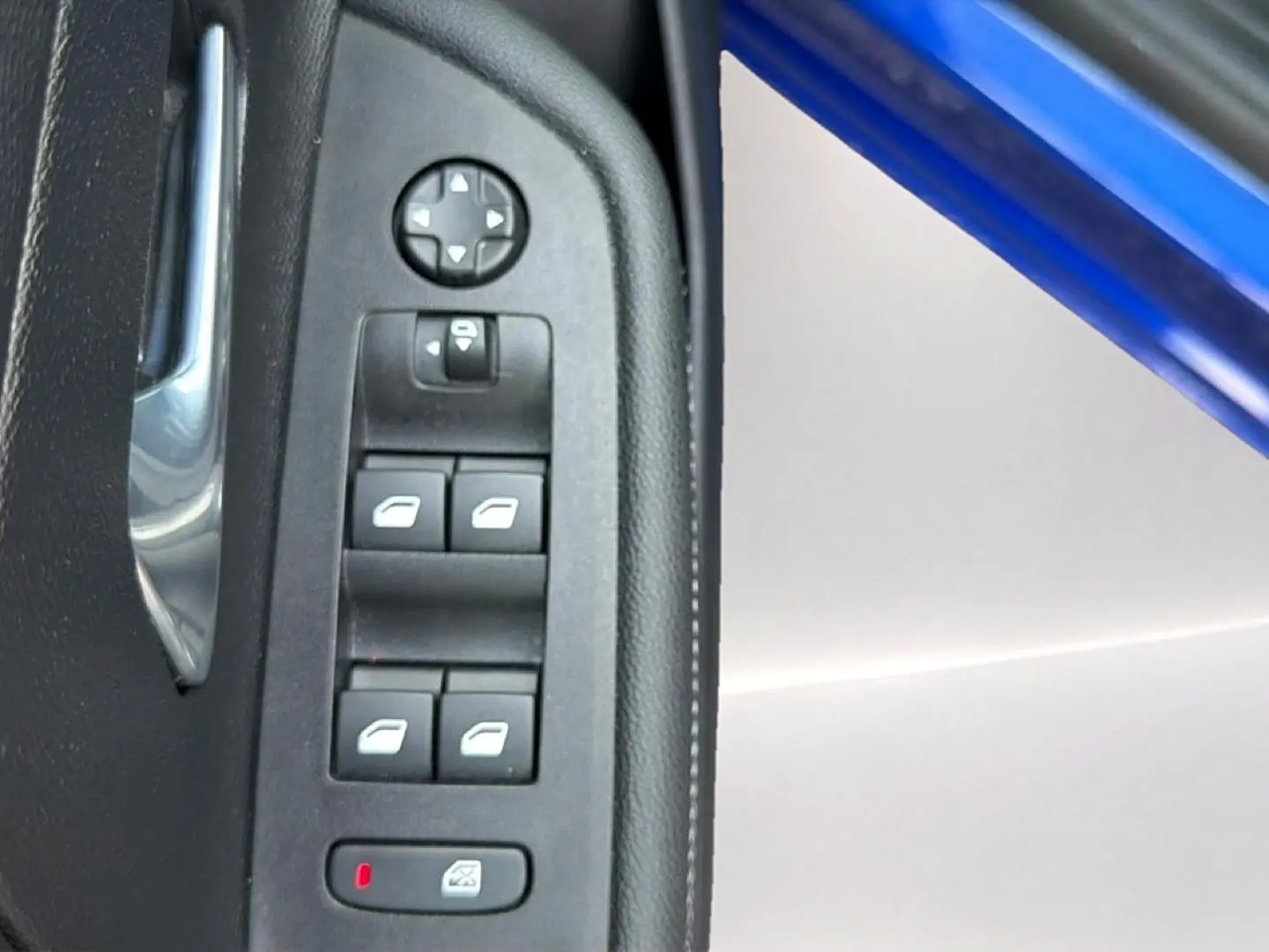 Gros plan sur les commandes des vitres et rétroviseurs côté conducteur d’un Opel Mokka Electric bleu 2025.