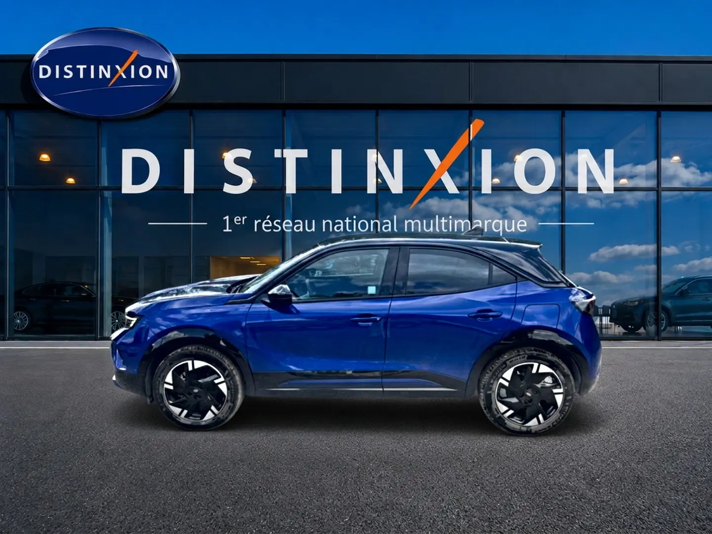 Vue de profil côté gauche d'un Opel Mokka Electric 156 GS bleu devant une vitrine Distinxion.